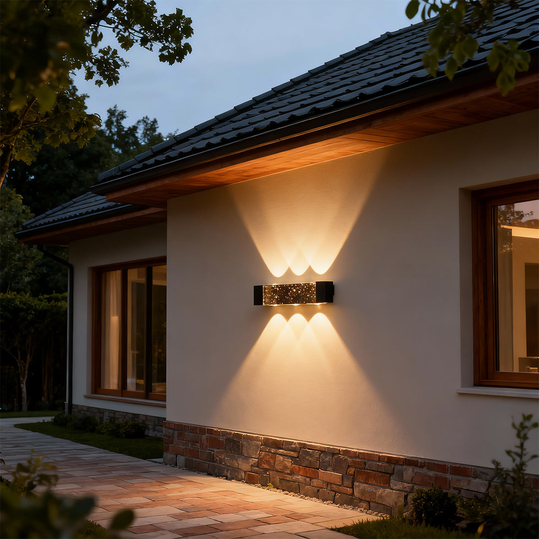 Elegant up down wall light with glass shade chandelier design illuminating traditional home exterior at twilight.