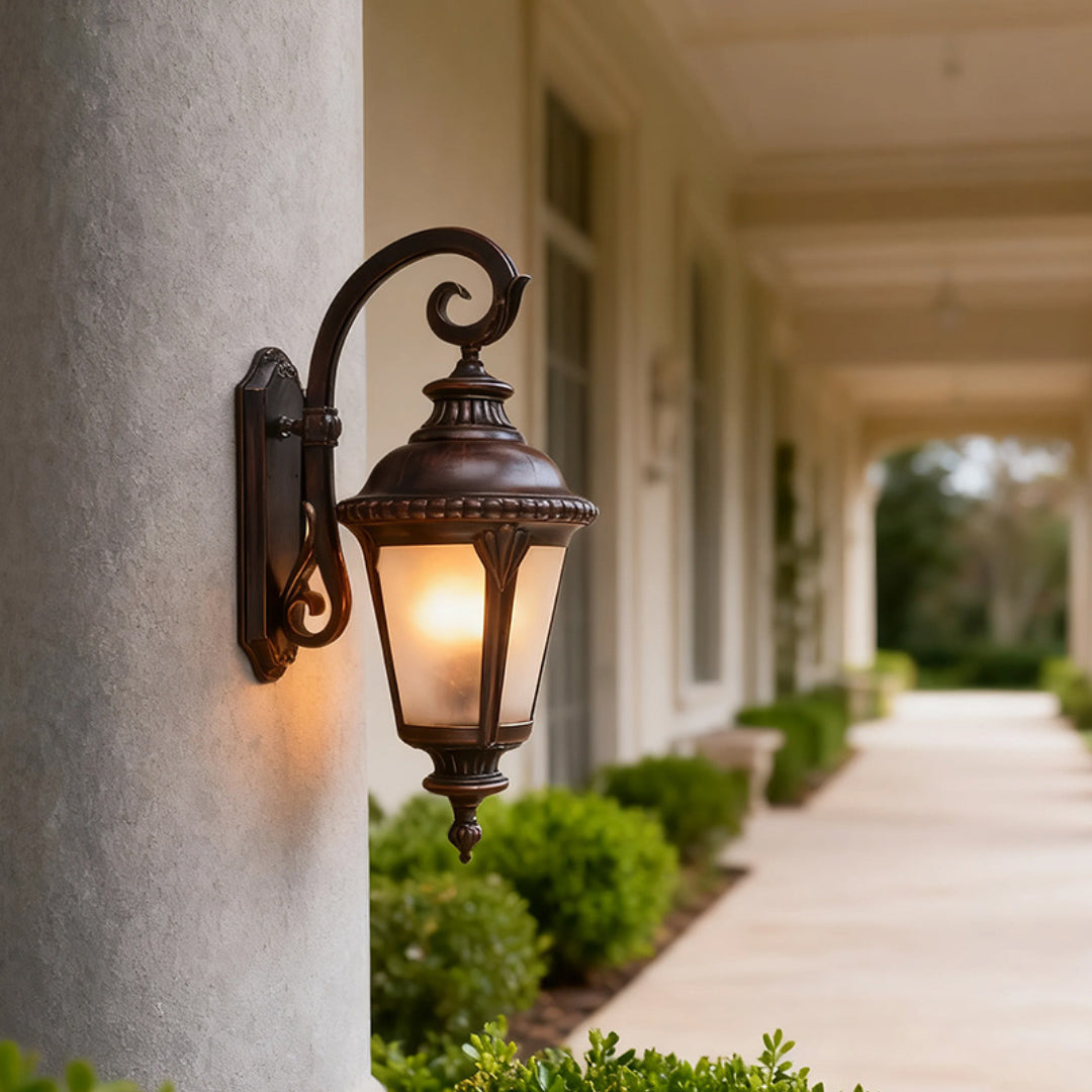 Elegant vintage outdoor wall sconce providing ambient light along covered colonnade with white pillars