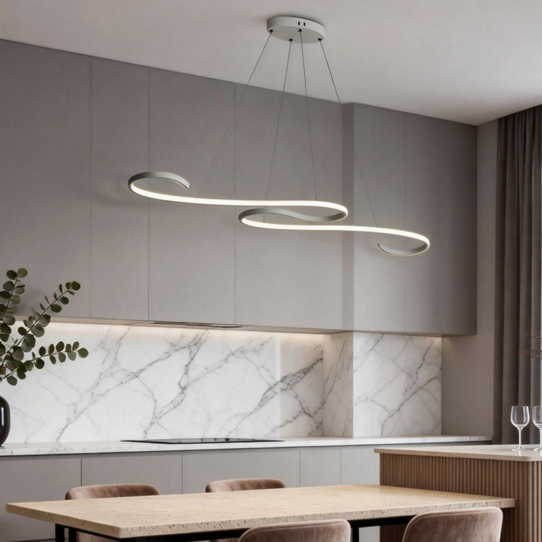 Elegant white chandeliers featuring a minimalist loop design, illuminating a dining area with marble backsplash.