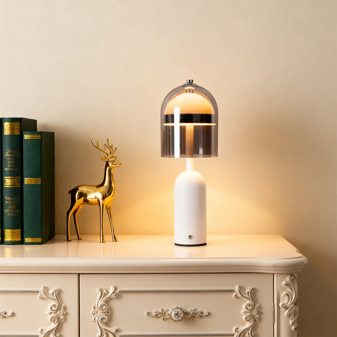 Elegant white glass shade table lamp illuminating a decorative antique nightstand with books and a golden deer statue. 