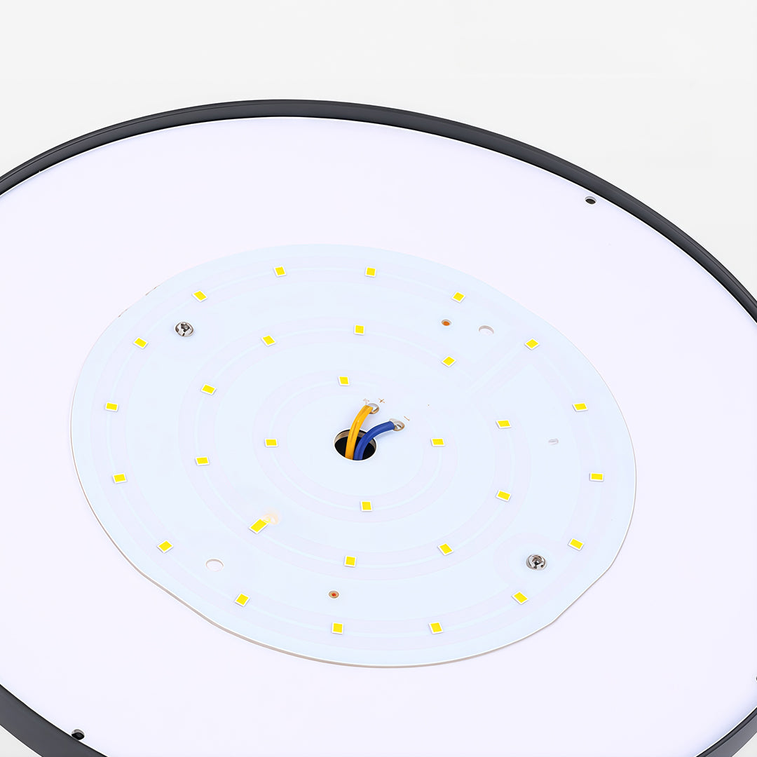 Energy-efficient black outdoor wall light with a solar panel, mounted along a garden fence.