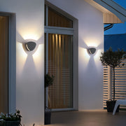 Warm illuminated wall light outdoor fixtures mounted on a modern home entrance exterior.