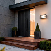 Warm-toned outdoor wall lights LED illuminating a modern entryway with a layered metal housing design.