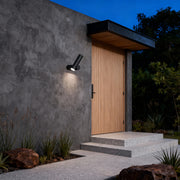 Minimalist outdoor spotlight wall lights mounted near an entryway, casting focused beams along the pathway.