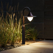 Evening garden pathway illuminated by curved bollard lights creating warm ambient lighting atmosphere
