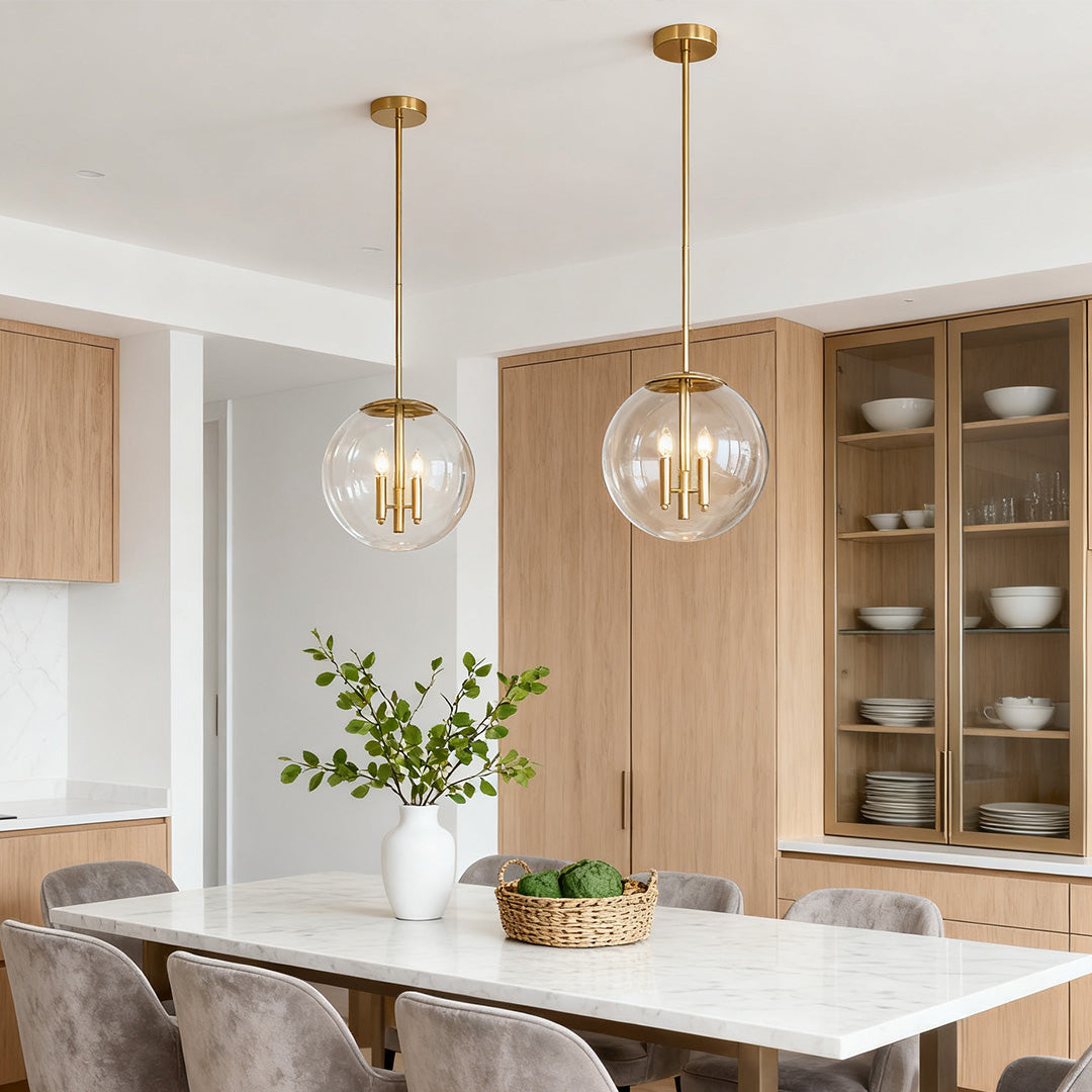 Clear globe pendant light fixture with exposed bulbs illuminating a modern dining area with light wood cabinetry and neutral chairs.