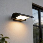 Exterior down wall lights mounted on a white outdoor wall with a modern black curved shade and warm downward glow.