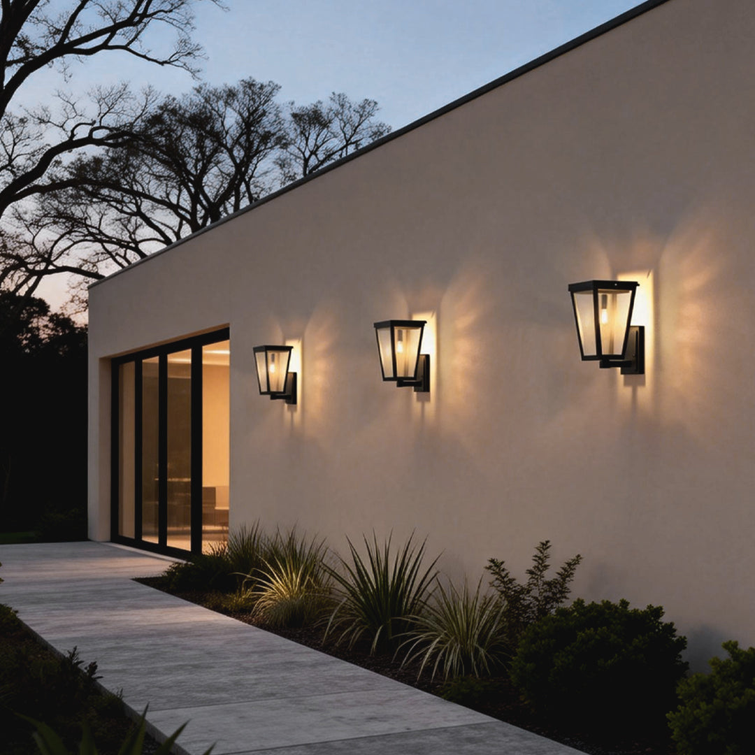 Exterior LED wall lantern with modern black frame mounted on a light-colored wall, illuminating a residential entrance.