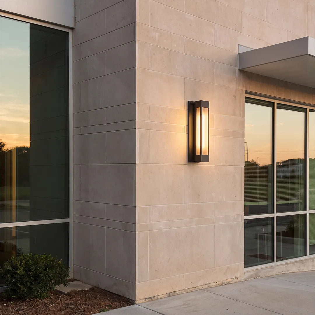 Exterior LED wall sconce lighting installed on a light stone wall beside a modern glass exterior door.