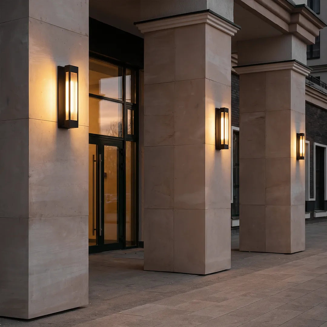 Exterior LED wall sconce lighting arranged along stone columns at a contemporary building entrance.