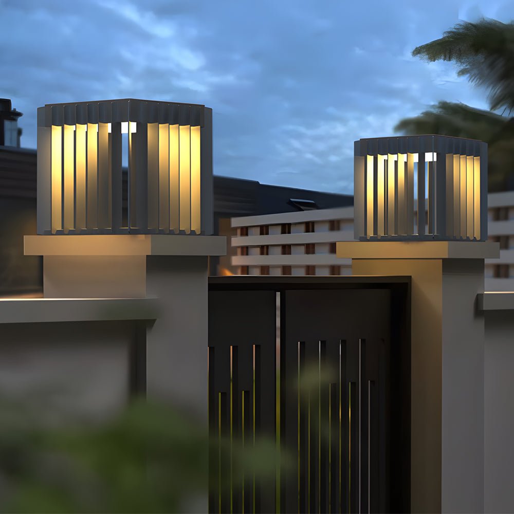 Exterior pillar lights illuminating a minimalist garden pathway with concrete pillars.