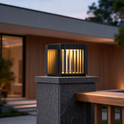 Exterior pillar lights illuminating a modern house entrance with wooden and stone accents at dusk.