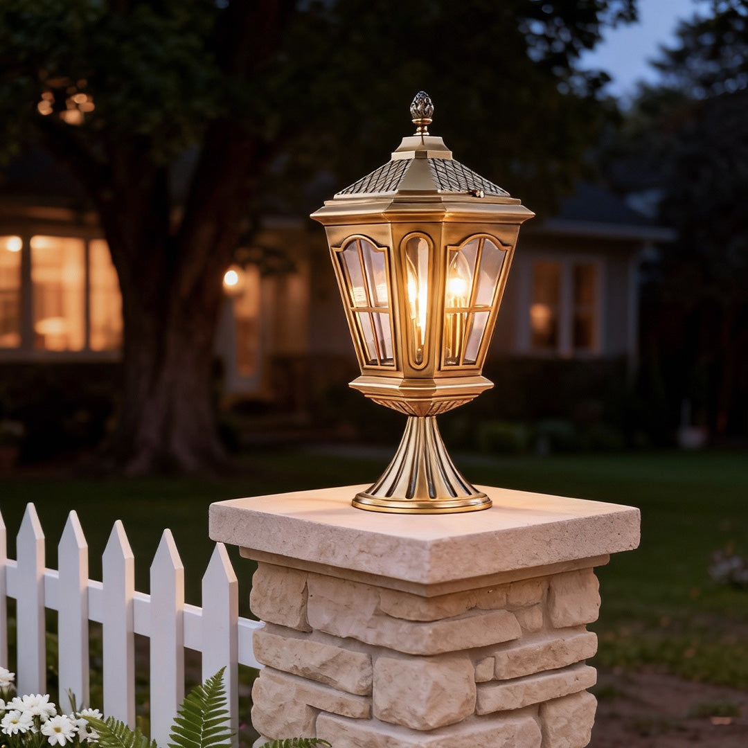 Exterior pillar mount lights casting a warm glow on a brick pillar in a cozy garden setting.