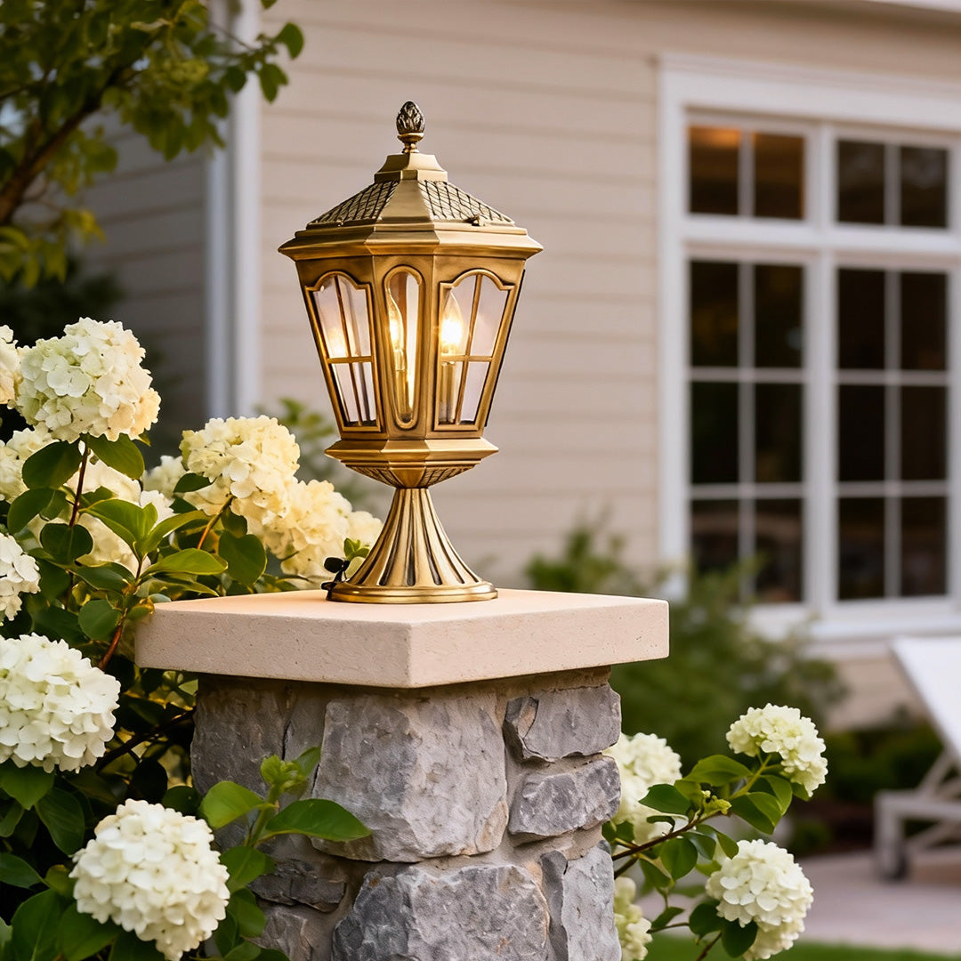Exterior pillar mount lights enhancing a garden entrance, surrounded by lush flowers and greenery.