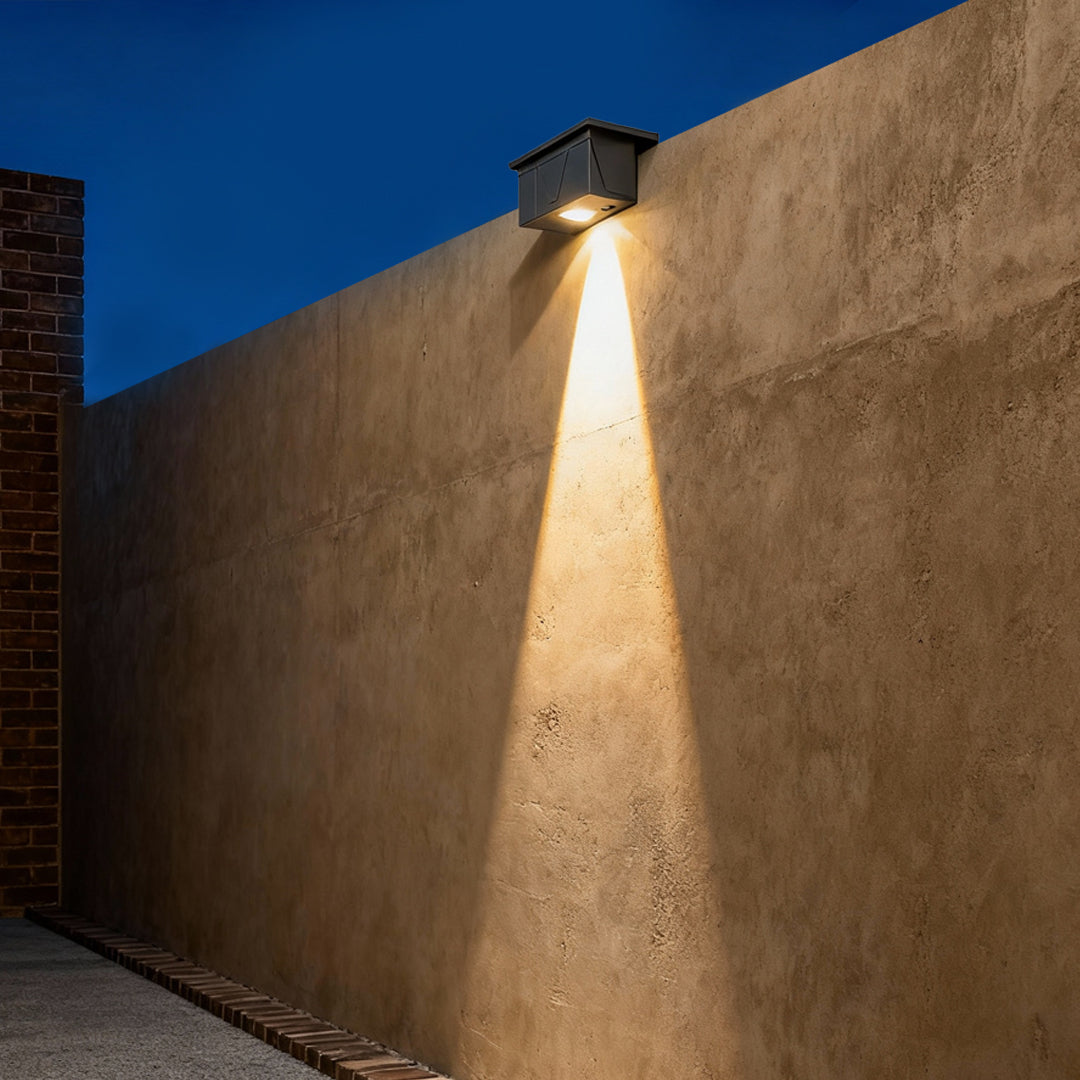 Multi-fixture exterior wall wash lighting illuminating a long stone boundary wall with warm, even light spread.
