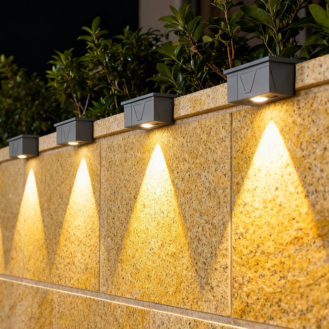 Exterior wall wash lighting creating layered illumination along a stone path wall for nighttime safety and ambiance.