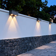 Single-beam exterior wall wash lighting fixture casting a tall, narrow light pattern on textured stone walls.