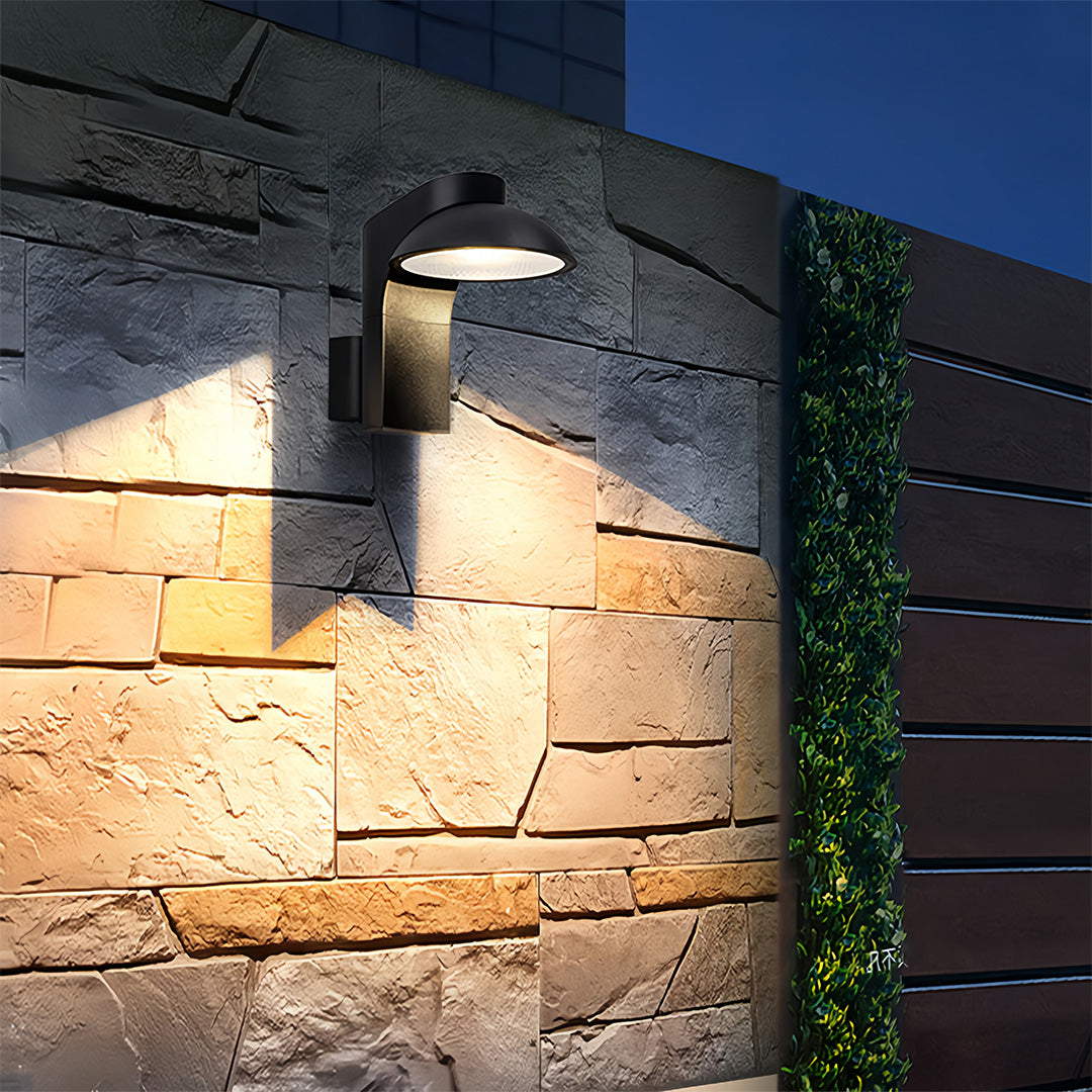 Extra large outdoor wall light illuminating textured stone wall at night.