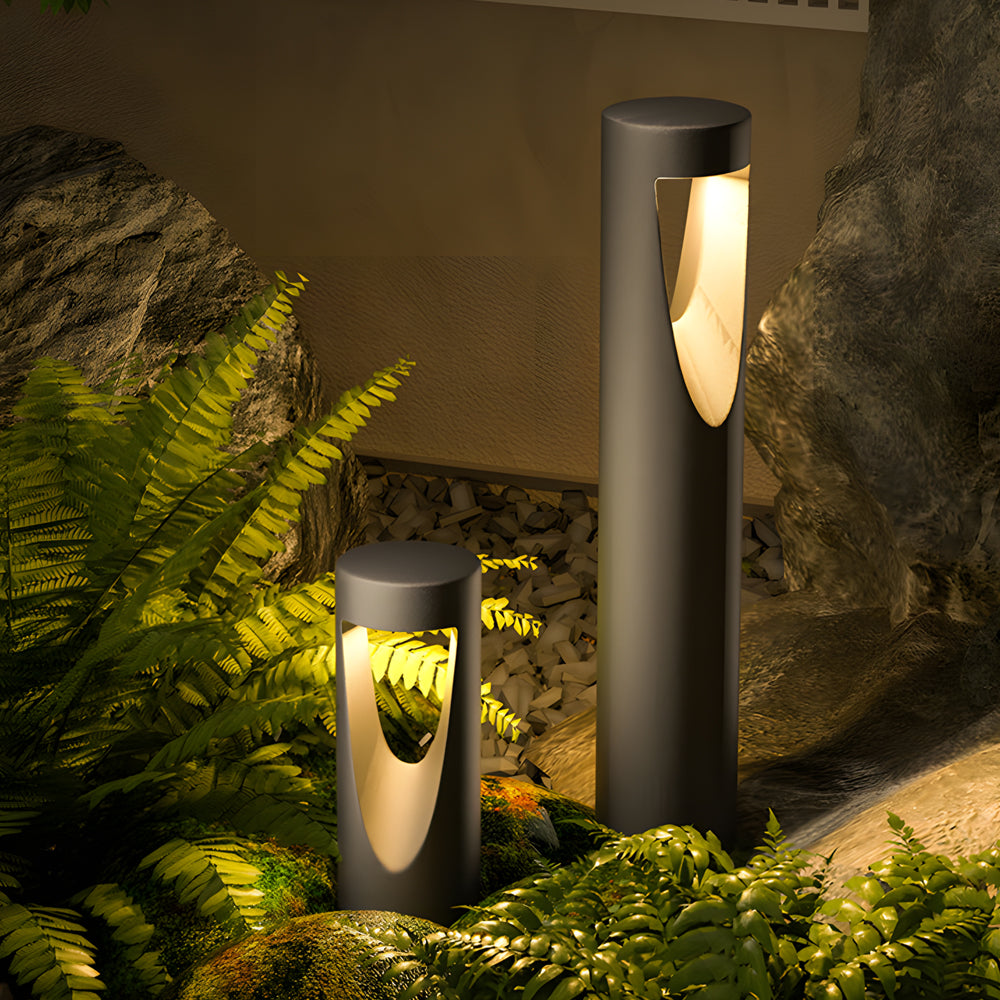Garden landscape lighting featuring cylindrical bollards illuminating tropical plants and stone pathway