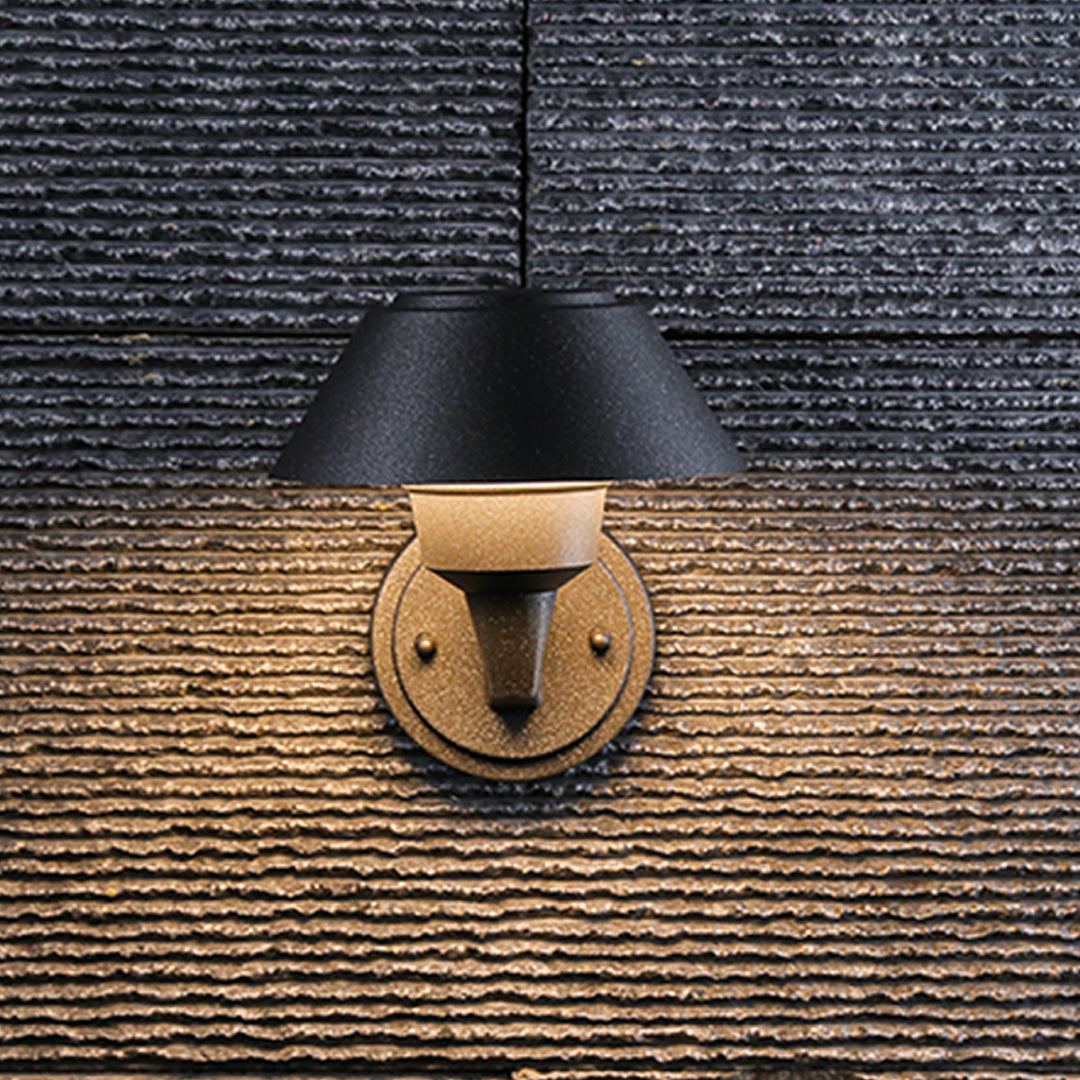 Modern black dome wall light with extending arm illuminating brick exterior wall at dusk