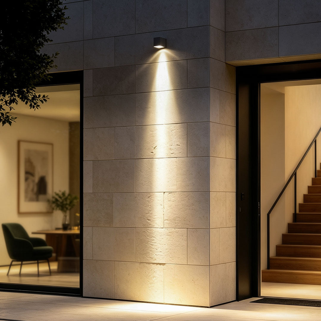 Facade spot lights illuminating a tall exterior wall beside a modern home entrance at night.