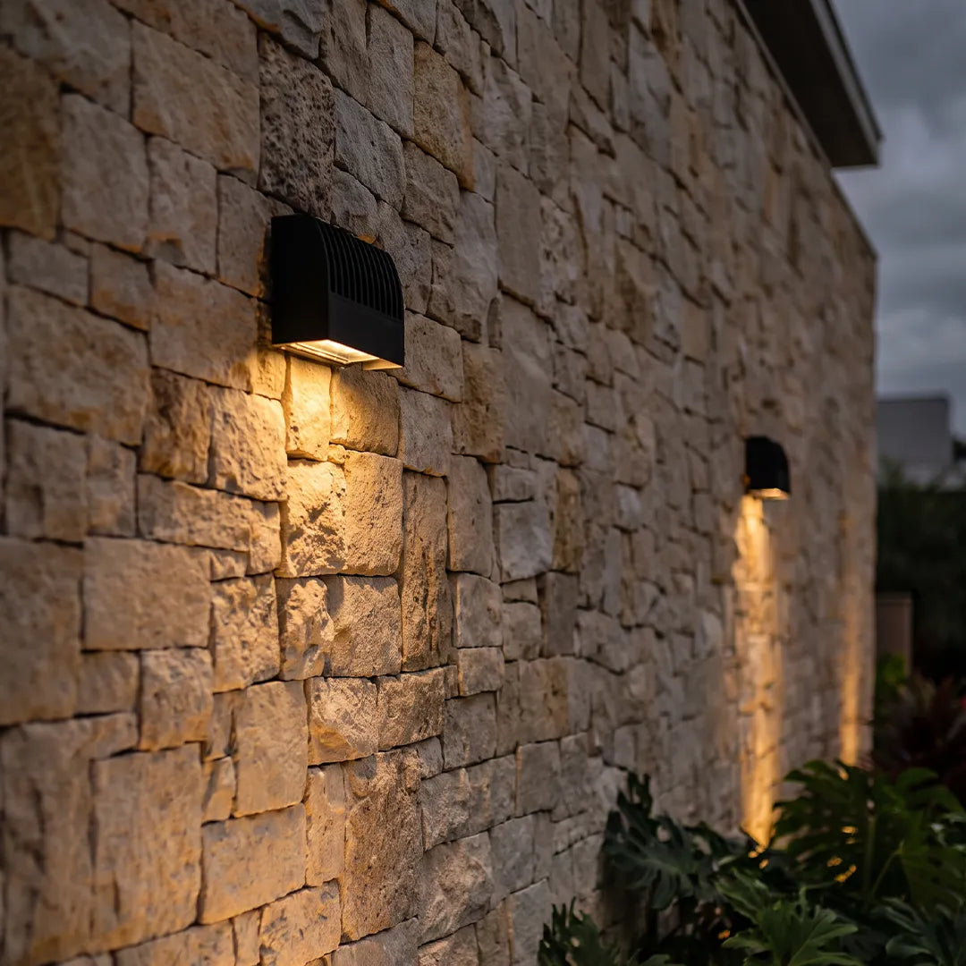 Facade spot lights casting warm downward beams on a textured stone exterior wall.