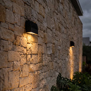 Facade spot lights casting warm downward beams on a textured stone exterior wall.