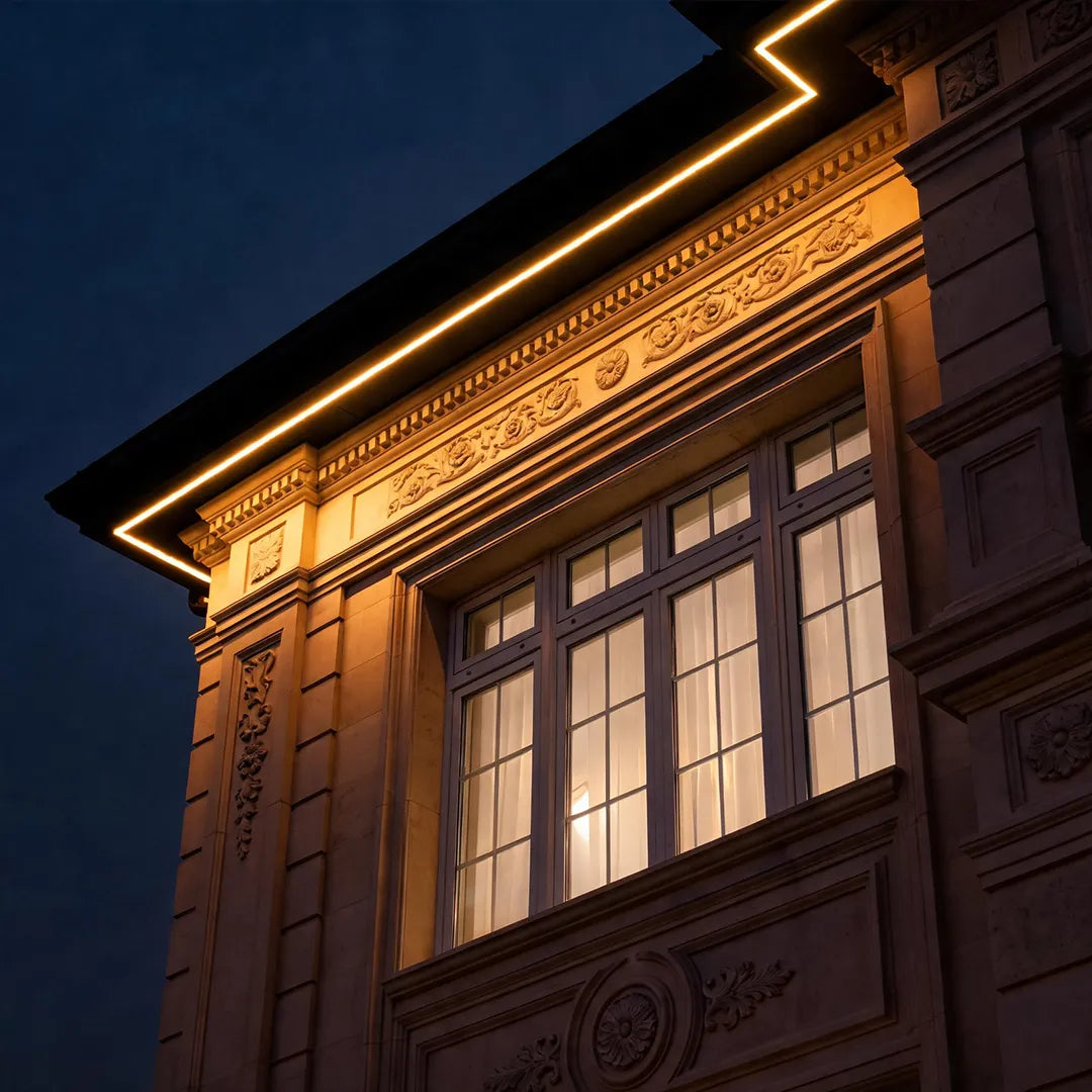 Facade wall washer light installed along an ornate building roofline, creating a warm linear glow that highlights the exterior architectural details.