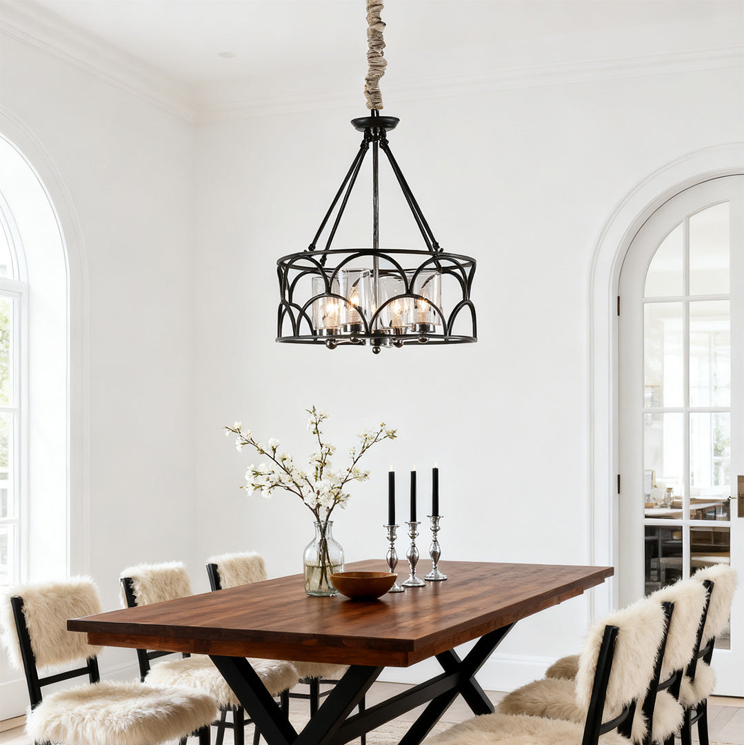 Elegant farmhouse-style chandelier with black metal accents, hanging over a large rustic wood dining table and sheepskin chairs.