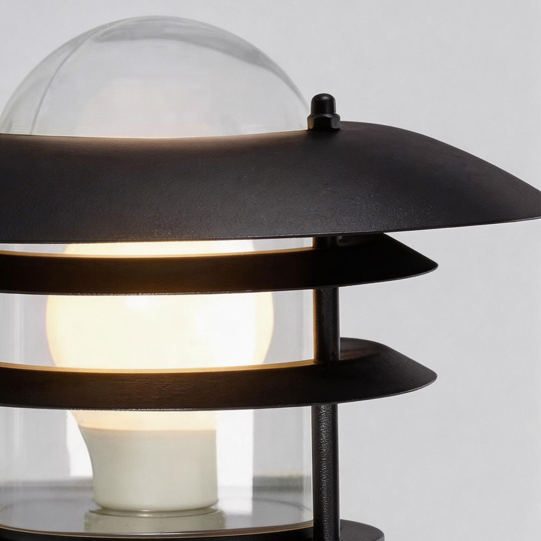 Close-up of farmhouse outdoor sconce showcasing its glass panel and warm light.