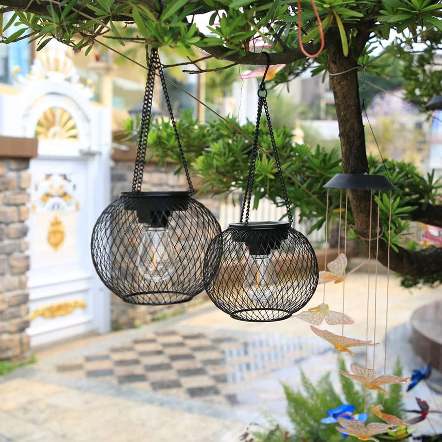 Decorative hanging lanterns suspended in outdoor garden setting with Mediterranean-style architecture
