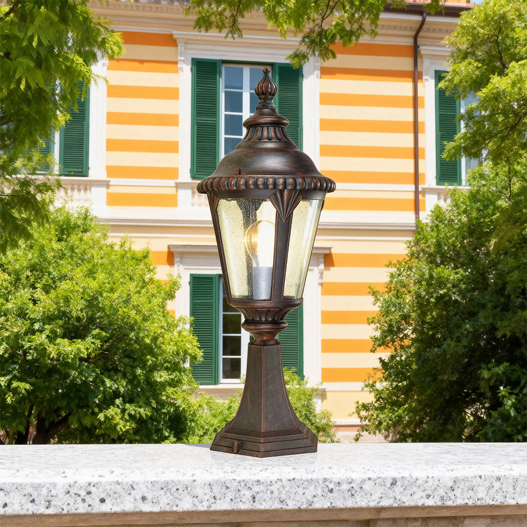 Fence pillar light brightening concrete pier near striped orange building with green shutters