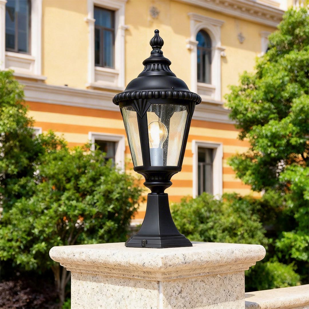 Fence pillar lights displayed on a stone pillar in a landscaped garden setting.