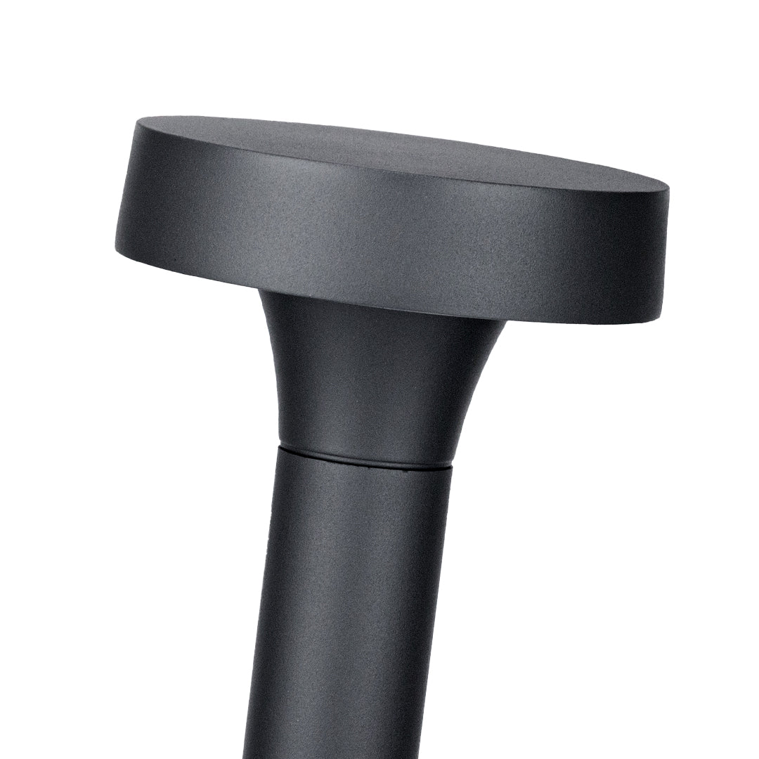 Close-up detail view of black flat-cap bollard light showing textured surface finish