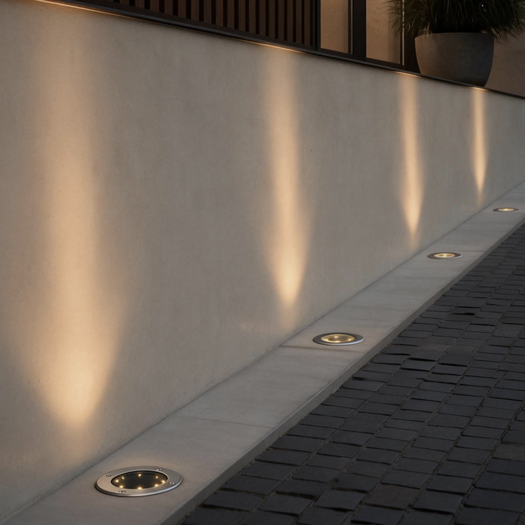 Flat garden lights providing subtle illumination along a concrete wall.