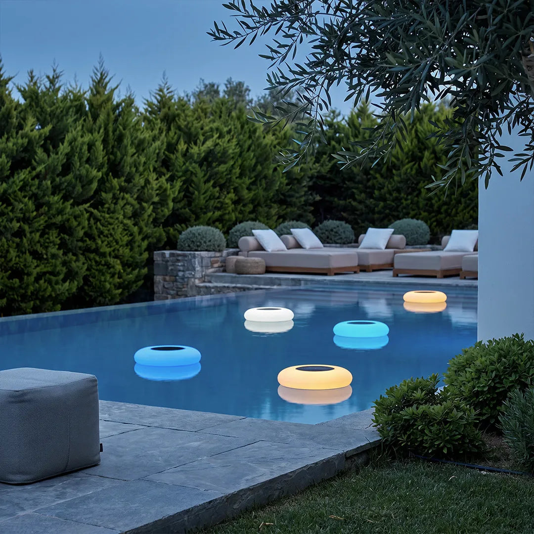 Floating pond lamp in a modern backyard pool, featuring a glowing round design in multiple soft colors for decorative outdoor ambiance.