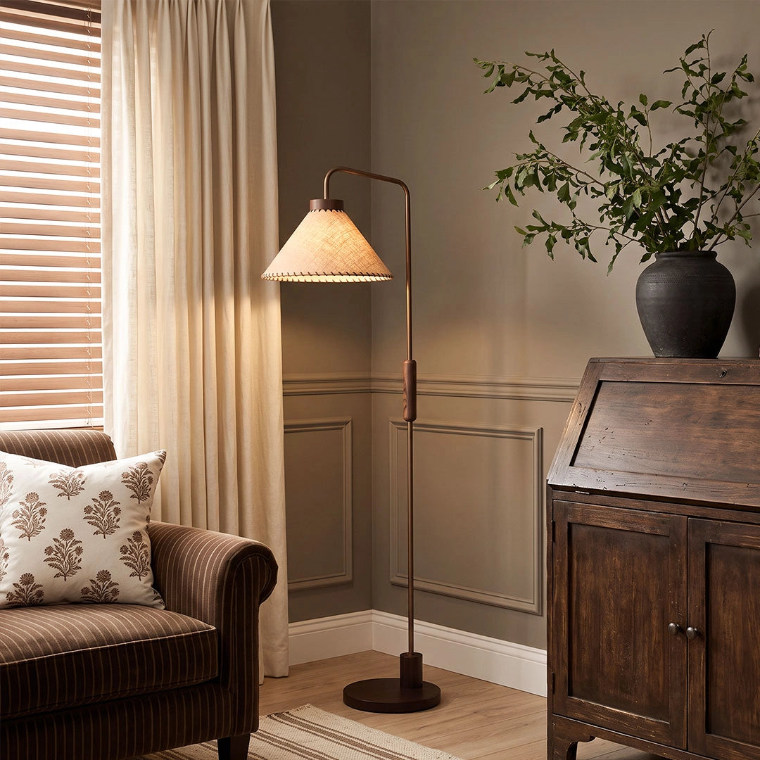 Floor decorative lamp beside an accent chair, featuring a slim wood stem and tapered fabric shade.