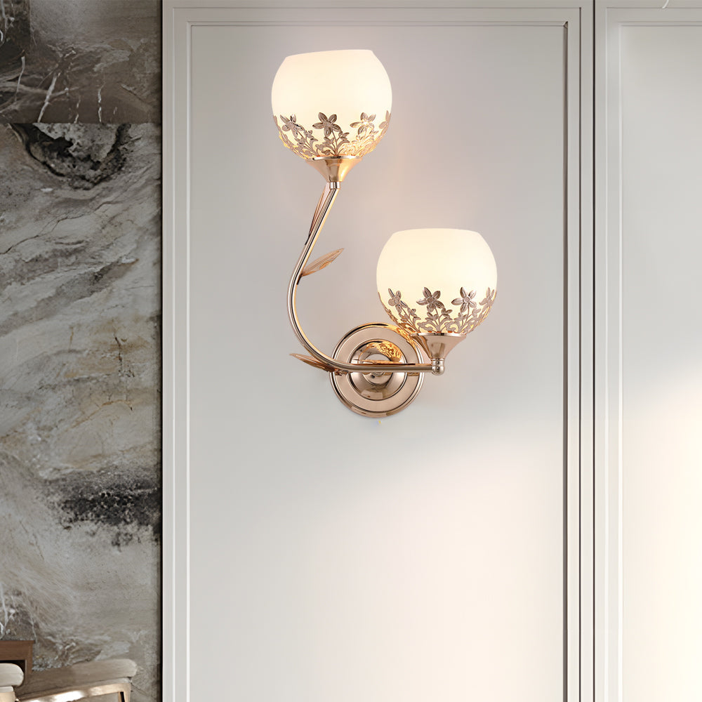 Elegant floral wall sconce with dual glass shades on a marble accent wall.
