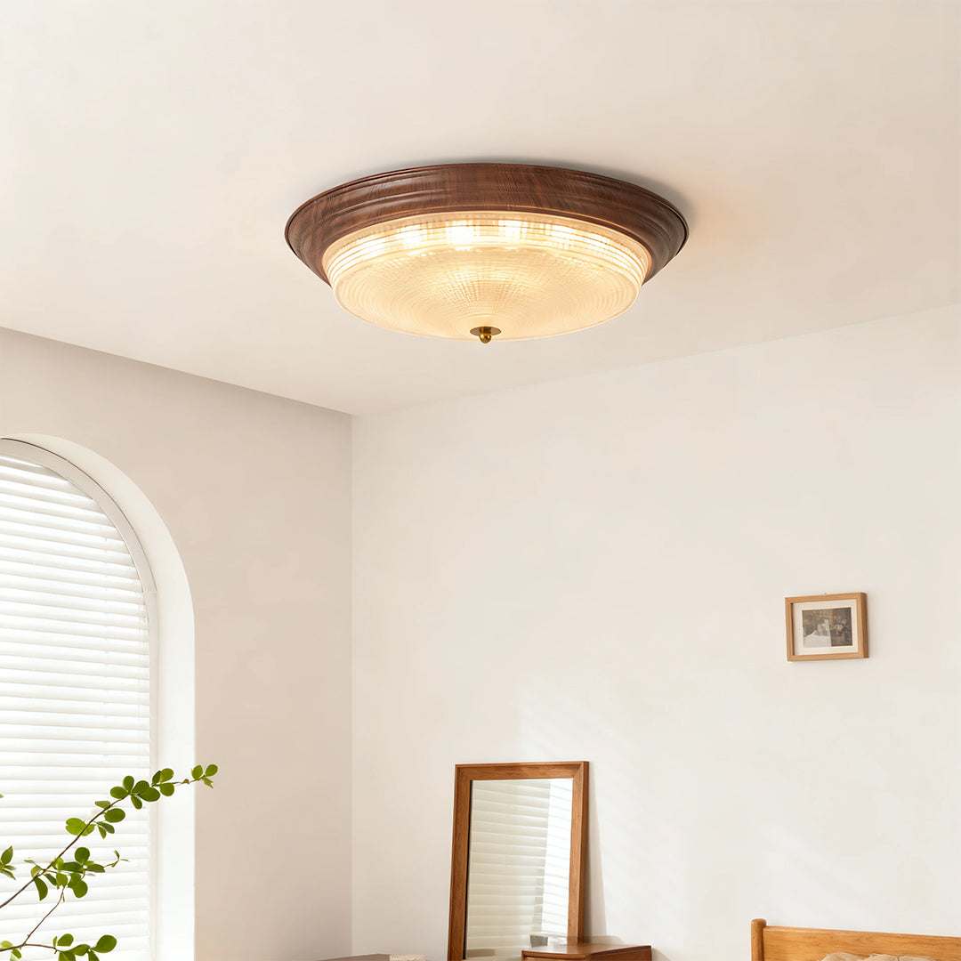 Flush mount dome light creating soft ambient glow in minimalist room with wooden furniture