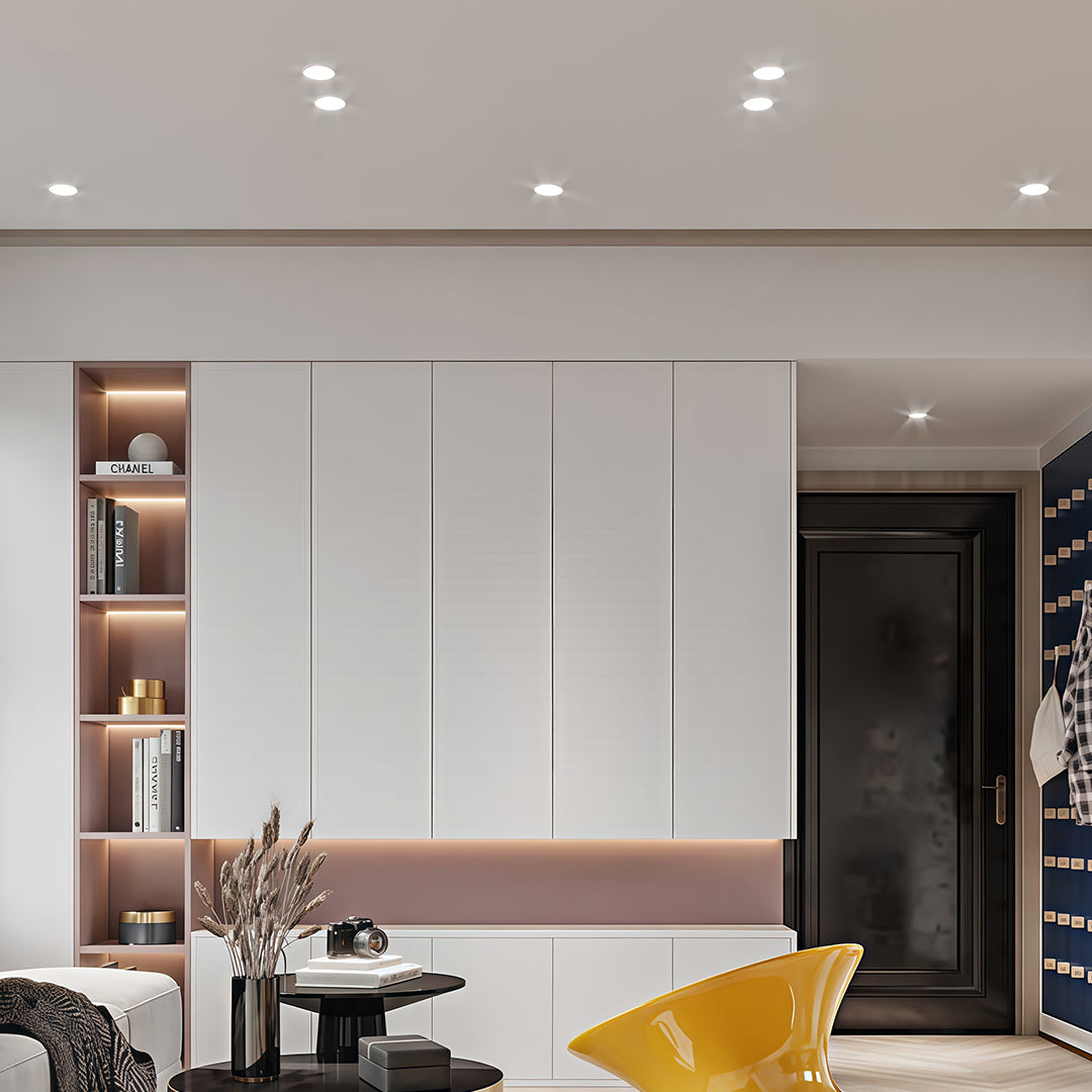 Flush mount spotlights illuminating modern kitchen with white cabinets, pink accents, and black door