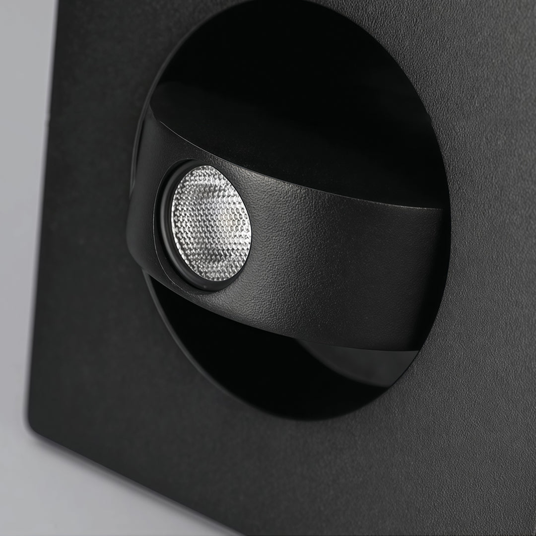 Close-up detail of black flush mount wall light featuring recessed LED spotlight and textured finish.