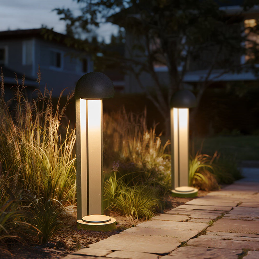 Contemporary bollard light creating focused ground illumination in natural garden setting