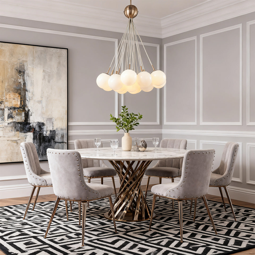 Bubble glass chandelier lighting up a formal dining area with gray wainscoting and a round table with a gold metal base.