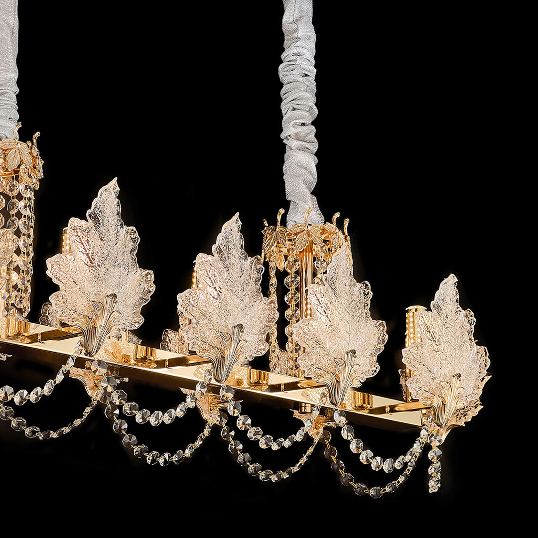French chandelier with crystal leaf details and golden finish on black background.