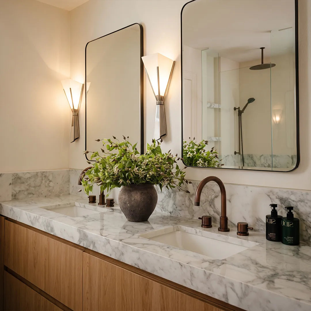 French wall sconces installed beside a bathroom mirror above a marble vanity.