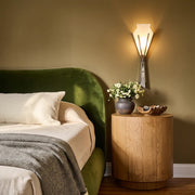 French wall sconces styled beside a bed with a green upholstered headboard and a warm bedside setting.