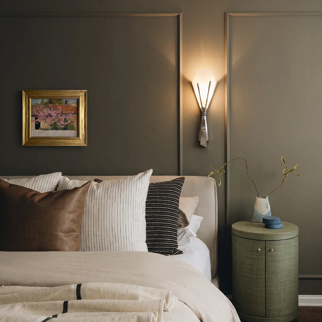 French wall sconces adding warm accent lighting above a bed in a modern bedroom.