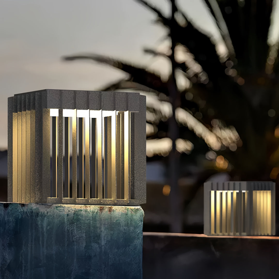 Tall modern front pillar lights illuminating a landscaped entrance with warm ambient lighting.