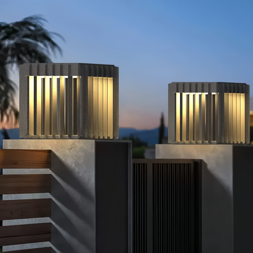 Warm modern front pillar lights installed along a contemporary fence line with clean architectural style.