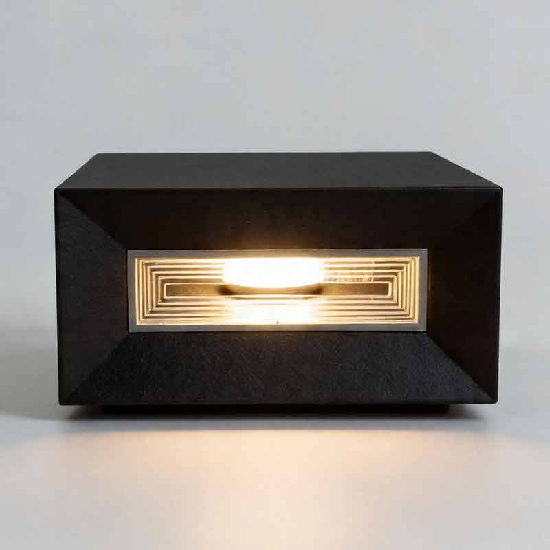 Front view of glowing square pillar lights showing warm light through the ribbed glass panel.